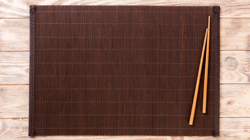 A pair of chopsticks on a brown bamboo placemat