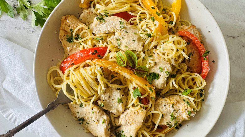 pasta with bell peppers, cheese, and chicken in a white bowl