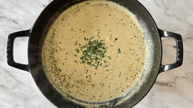 beige sauce with parsley in a black pan