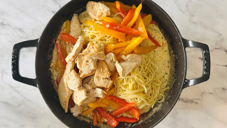 pasta with bell peppers, cheese, and chicken in a black pot