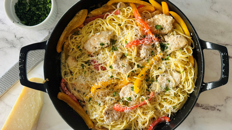 pasta with bell peppers, cheese, and chicken in a black pot