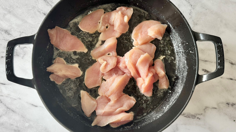 raw chicken in a black pan