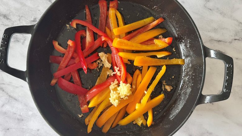 chopped bell peppers and garlic in a black pan