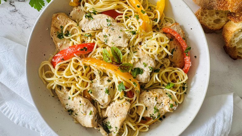 pasta with bell peppers, cheese, and chicken in a white bowl