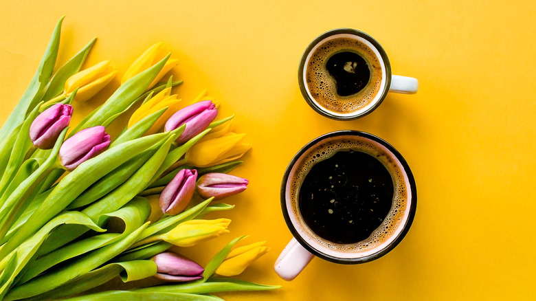 coffee mugs next to tulip bouquet