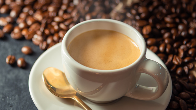 coffee with cream surrounded by coffee beans