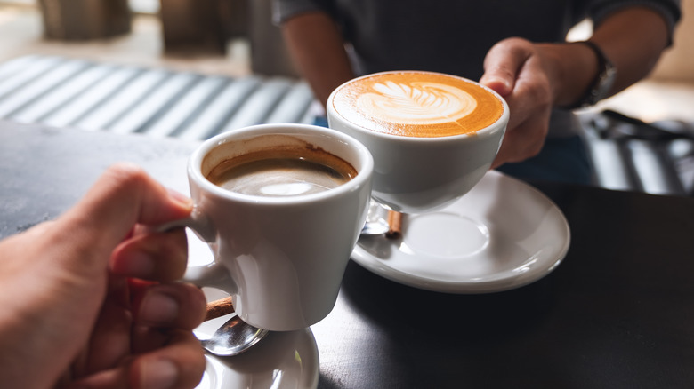 two coffee mugs clinking together