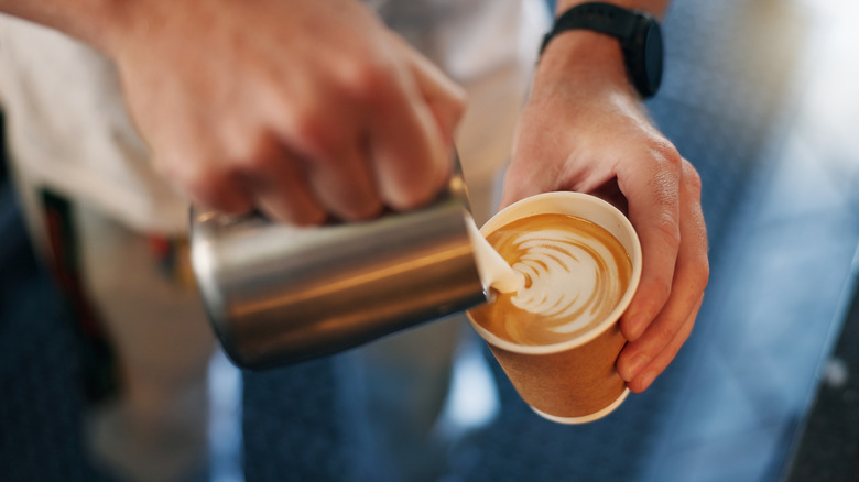 Pouring steamed milk into a to-go cup