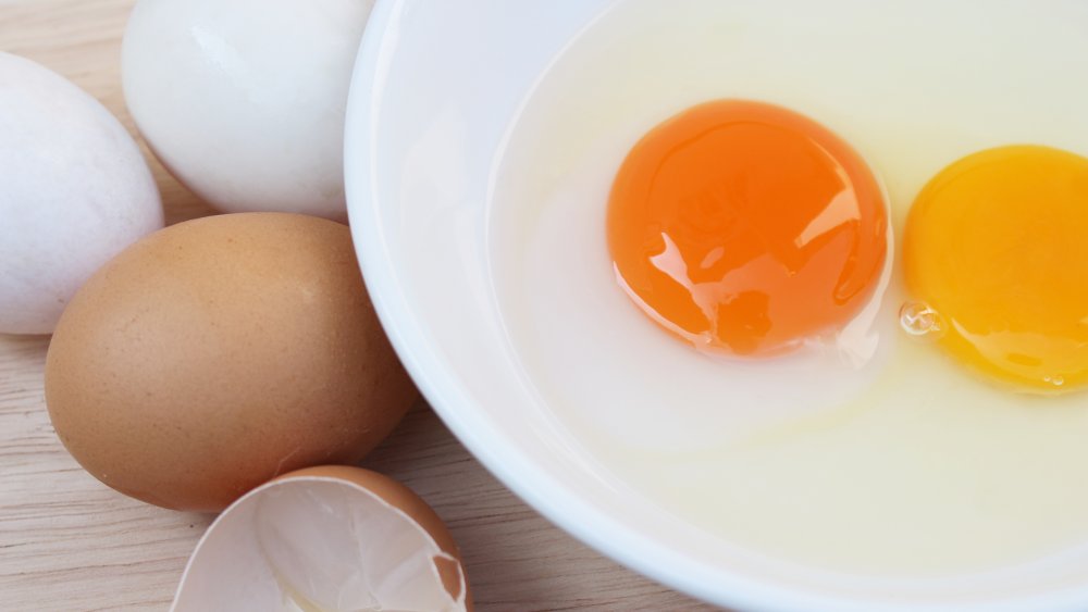 Bowl of cracked eggs with yolks with different colors