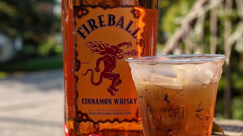 Fireball bottle with cream soda drink in plastic cup