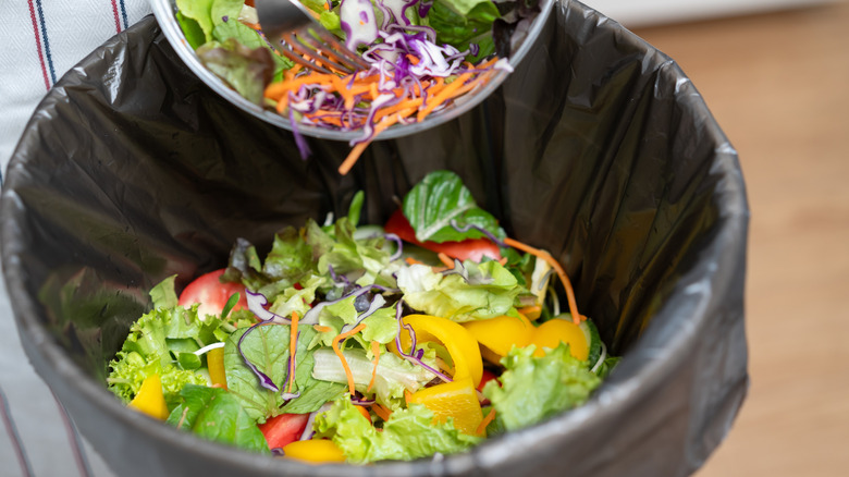 Food waste being emptied into a garbage bin