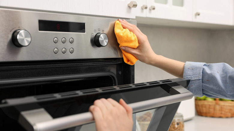 Woman cleaning an oven with a microfiber cloth