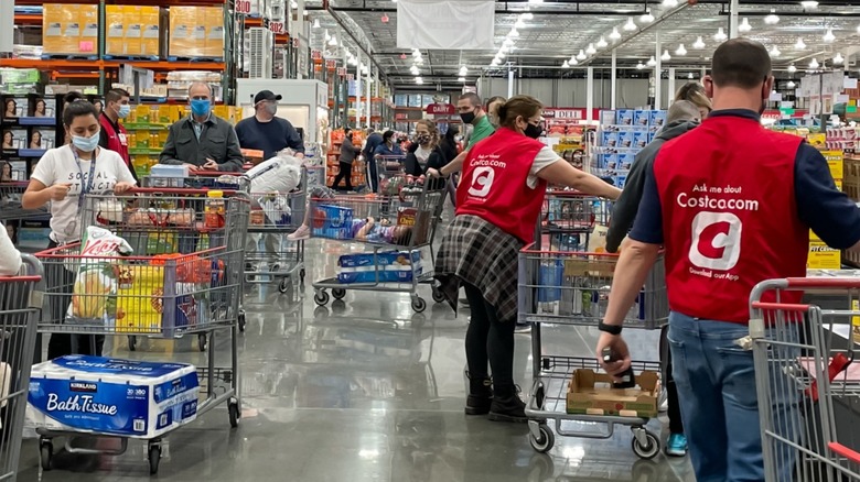 Customers at Costco in checkout aisle with carts wearing face masks