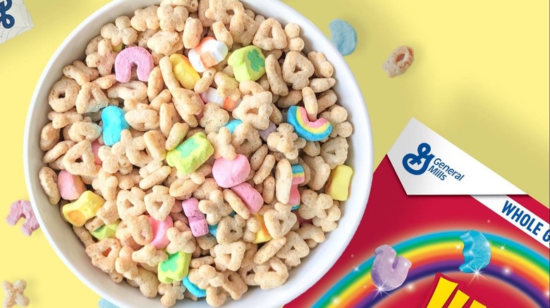 Bowl of Lucky Charms against a yellow background with box