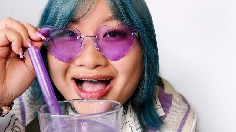 Soy Nguyen wearing purple heart sunglasses with drink