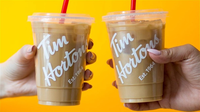 Tim Hortons iced coffees held out against bright yellow background