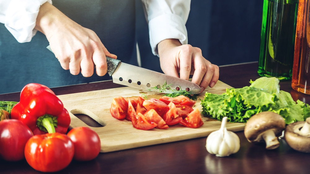 Person chops tomatoes on a cutting board