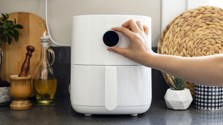 Person turning on the air fryer sitting on kitchen counter