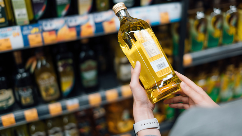 person shopping for olive oil at grocery store