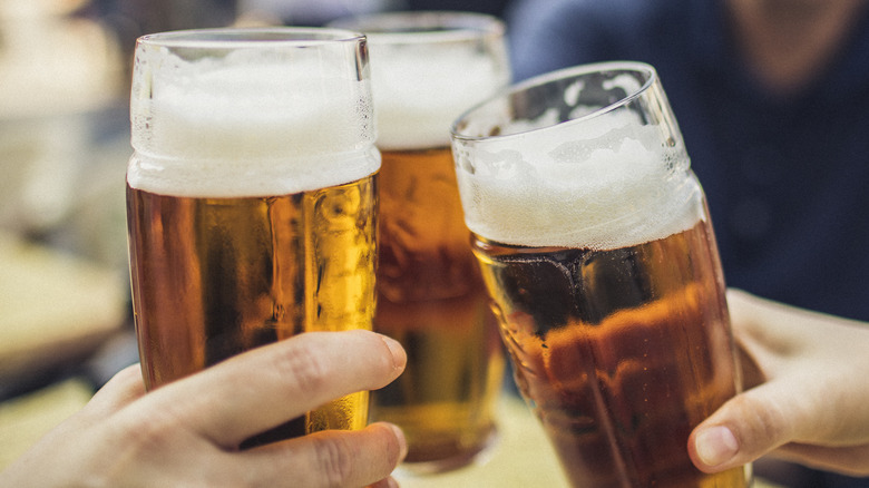 Three people clinking beer glasses