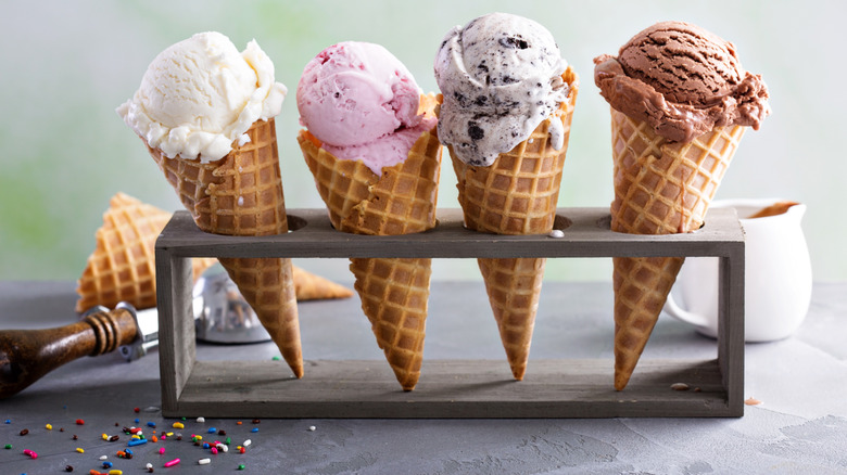 A metal ice cream holder with four different flavors of ice cream in cones