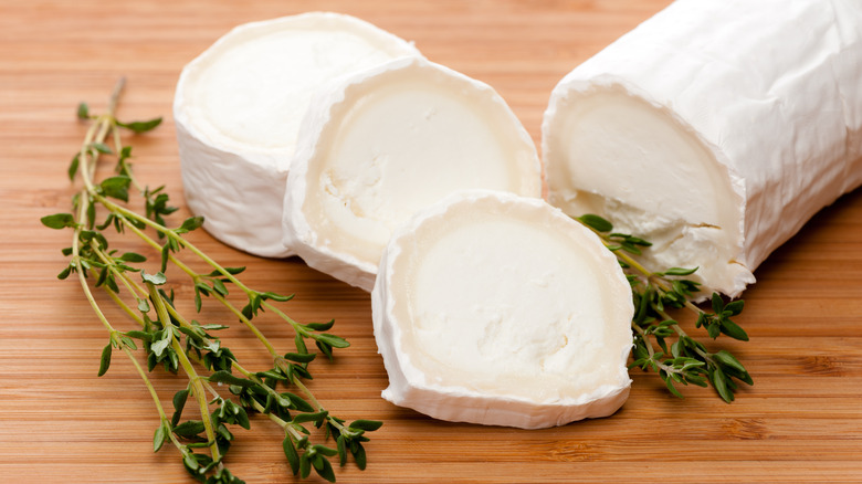 goat cheese slices with fresh herbs on wooden table