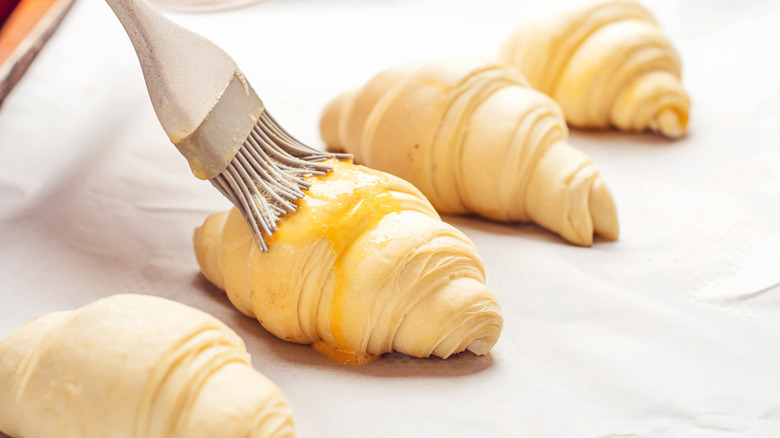 croissant being brushed with egg wash