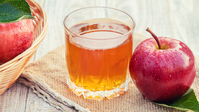 Glass of apple cider next to apples