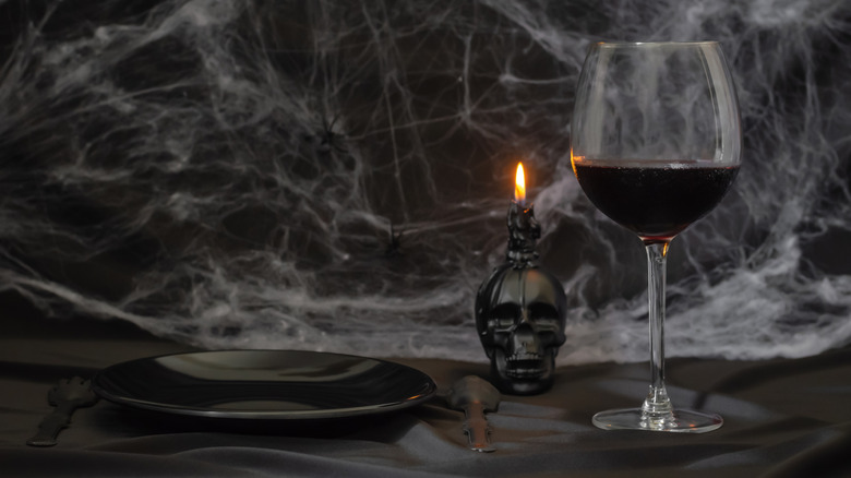 Glass of red wine in front of cobwebs and black background
