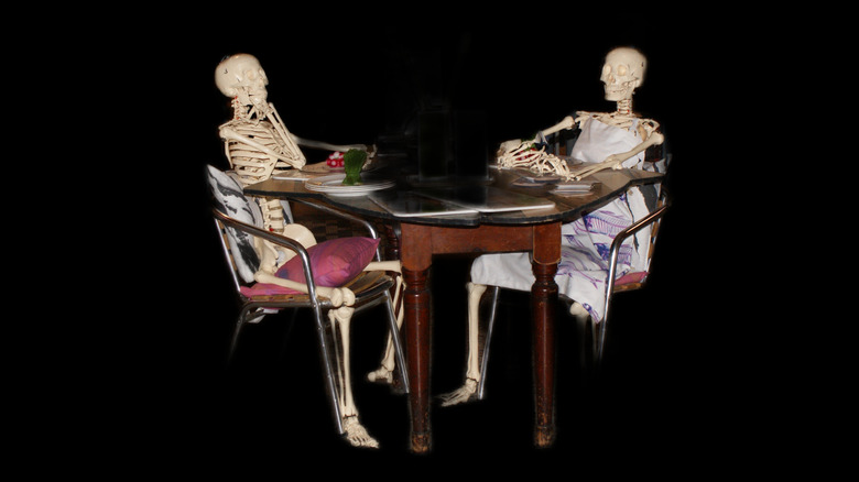 Skeletons seated at a dining table