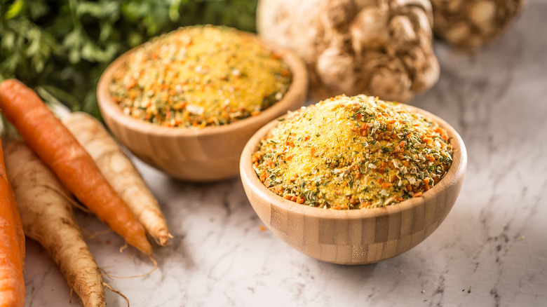 vegeta in a wooden bowl next to whole carrots and ginger