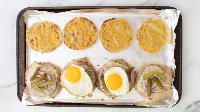 cuban-style breakfast sandwich halves garnished with onions, pickles, and a fried egg