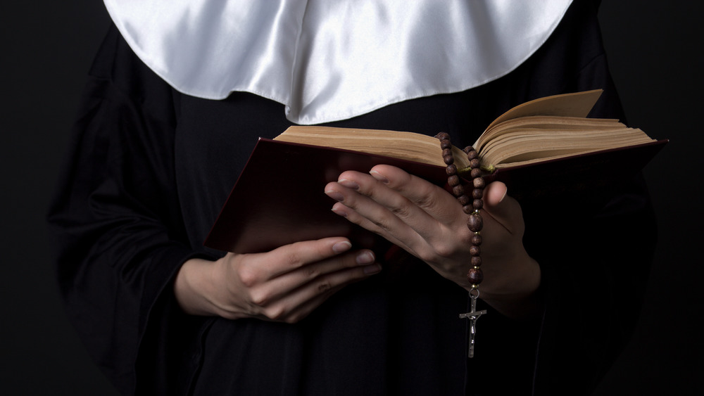 Nun with hands on book