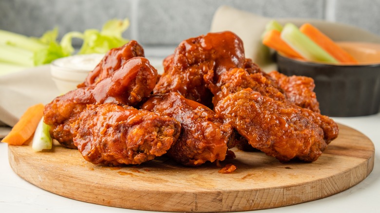 Sauced buffalo wings on wooden board with carrot sticks