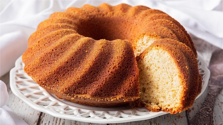 Bundt cake on a white platter with a slice cut from it