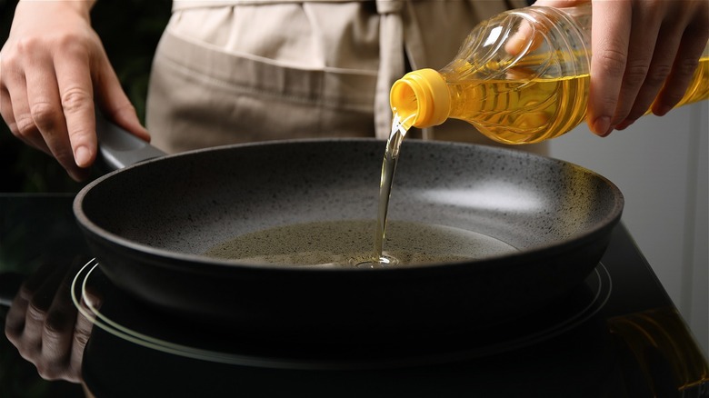 hands pouring oil into pan