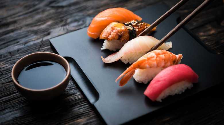 4 stykker nigiri sushi på tallerken med spisepinde