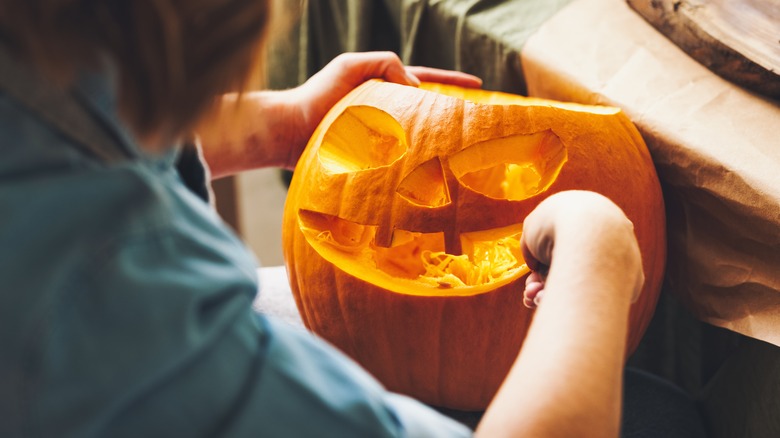 girl carving a pumpkin face
