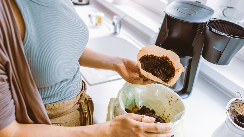 Person cleaning discard grounds from a drip coffee maker.