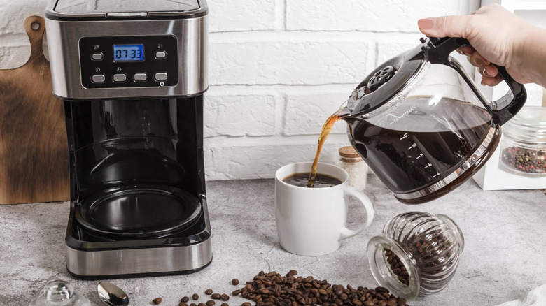 Person pouring freshly made coffee from a pot into a cup.