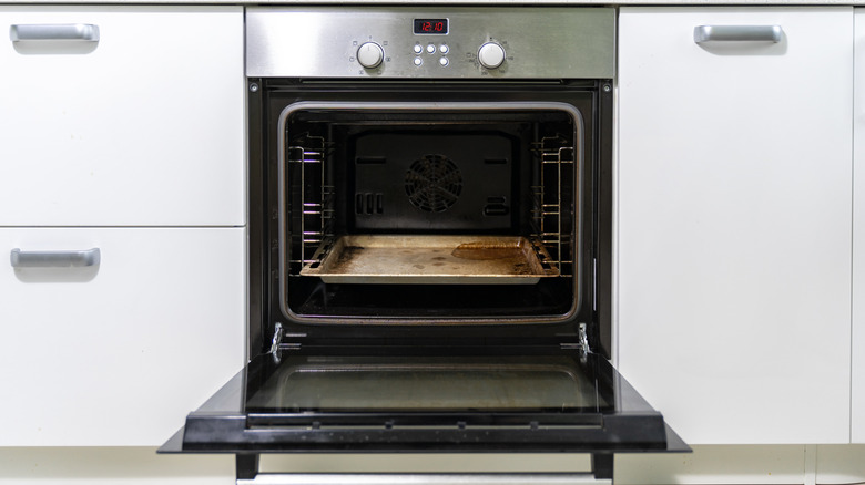 Open oven with greasy drip pan.
