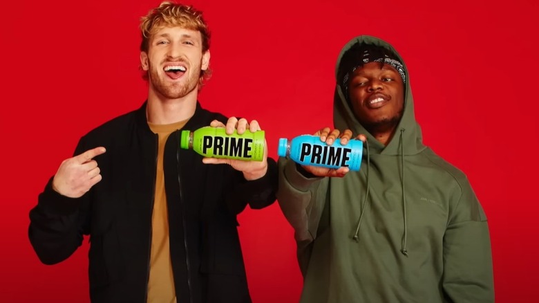 Logan Paul and KSI holding up bottles of Lemon Lime and Blue Raspberry PRIME hydration drinks