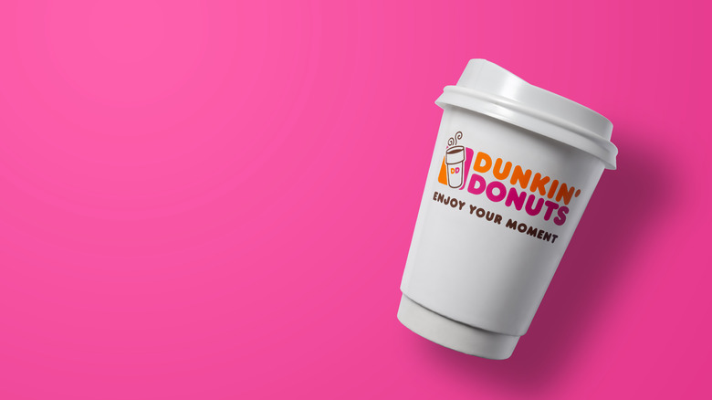 A Dunkin cup with logo on pink background