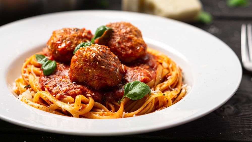 A bowl of spaghetti and meatballs with basil