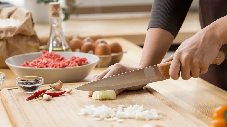 woman cutting onions on board