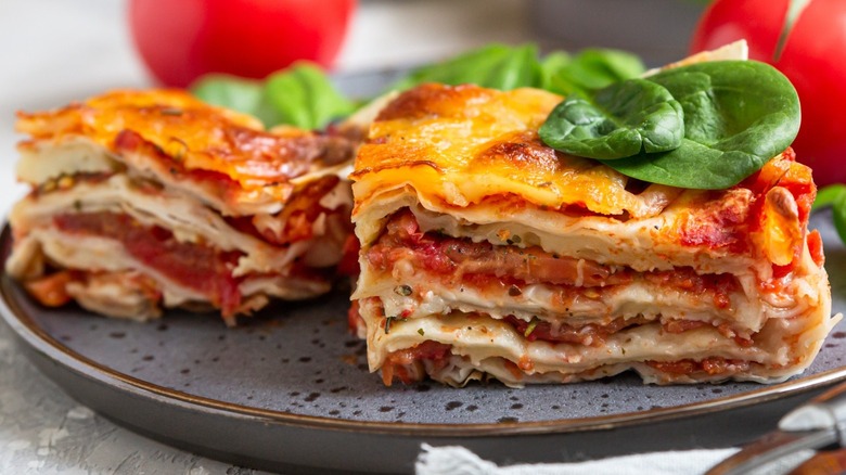 Slice of lasagna on a plate with basil leaves