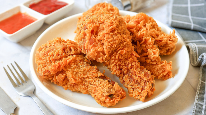 Crispy fried chicken drumsticks on white plate with sauces