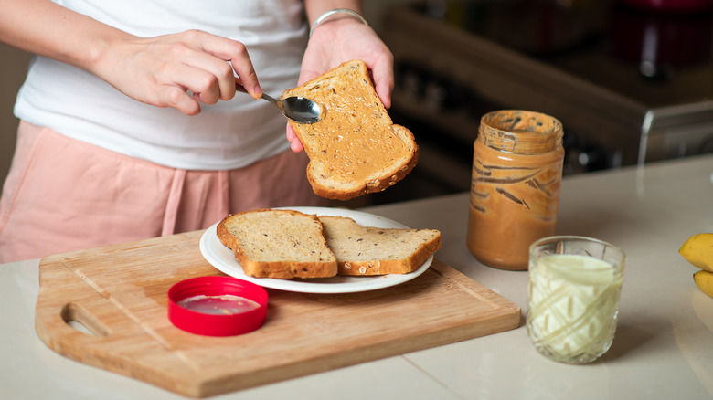woman making peanut butter sandwich on cutting board