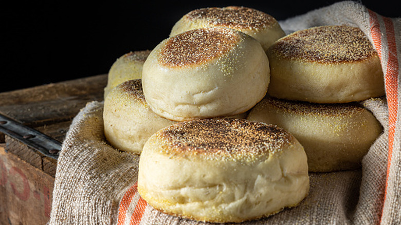Pile of rustic English muffins in a burlap bag on a wooden crate