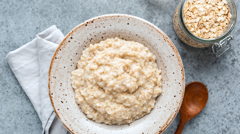 A bowl of porridge next to a jar of oats